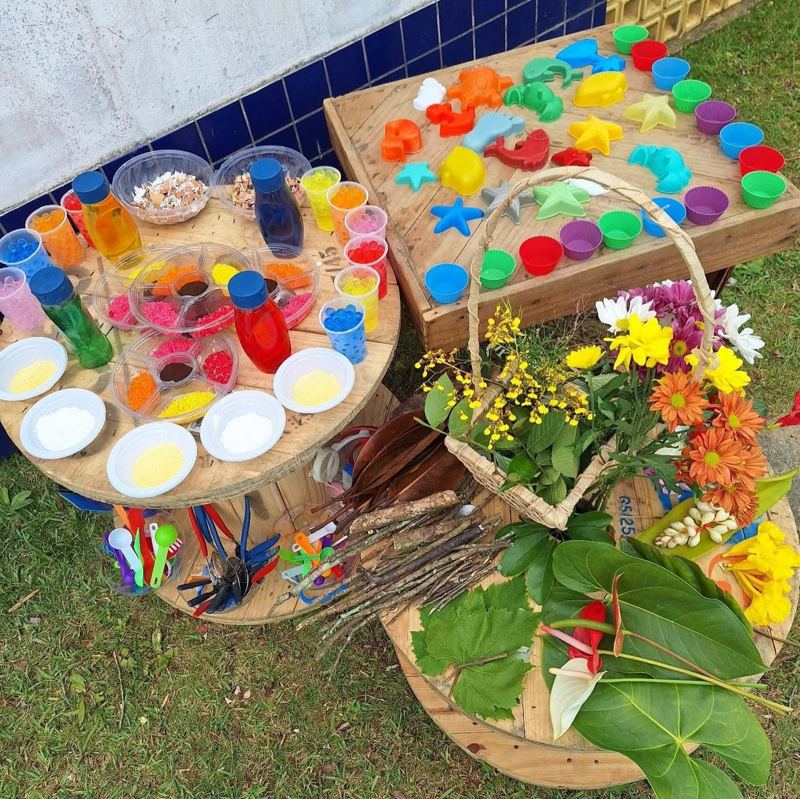 Espaço estético ao ar livre com carretéis, flores, folhas e forminhas montado por Edineia
