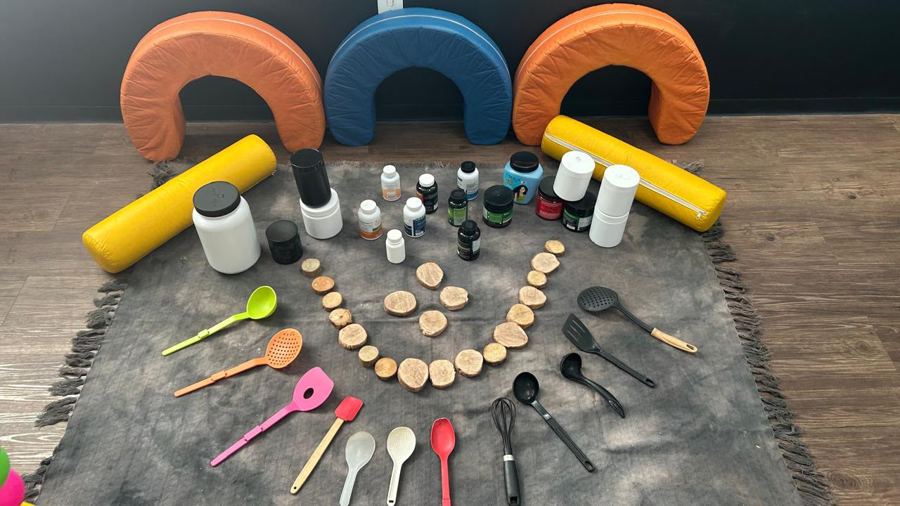 Espaço com potes, utensílios de cozinha e rodelas de madeira sobre tapete cinza