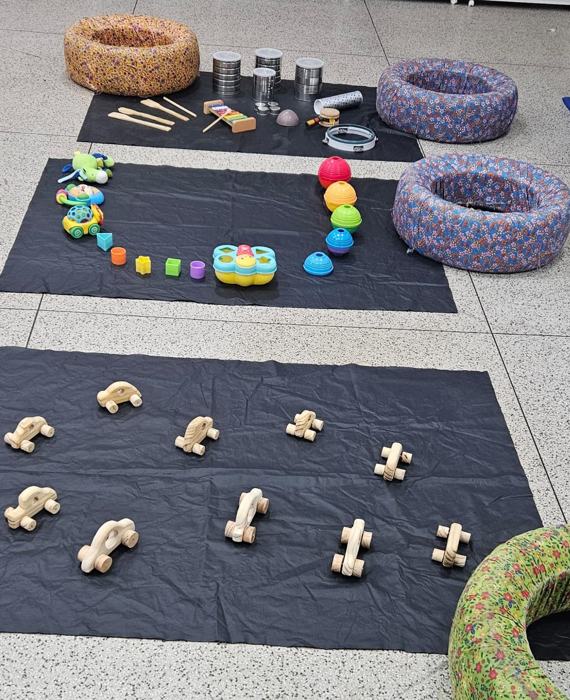 Espaço para bebês com carrinhos de madeira, instrumentos e almofadas